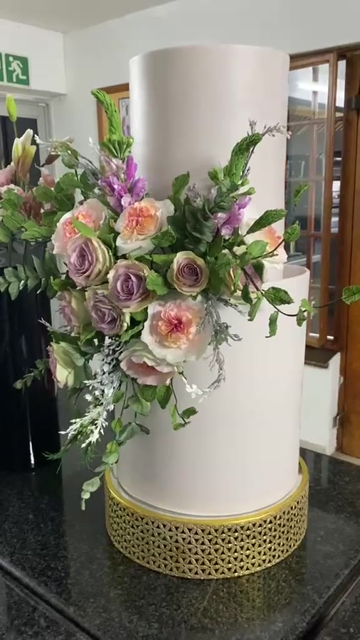 Tiers of silk-smooth cake crowned with hand-sculpted sugar and chocolate flowers, each petal edible, exquisite, and irresistibly romantic, a showstopper as delicious as it is beautiful